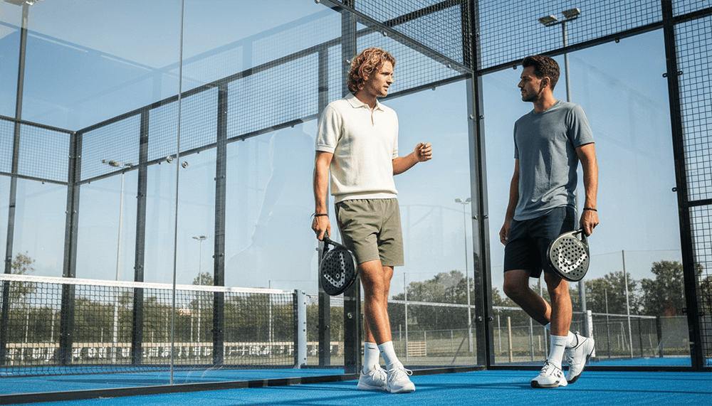 Beginnende padelspelers op een padelbaan met rackets in de hand